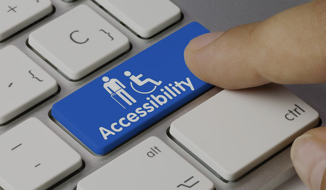 Foto de teclado de PC con una tecla azul con iconos sobre discapacidad