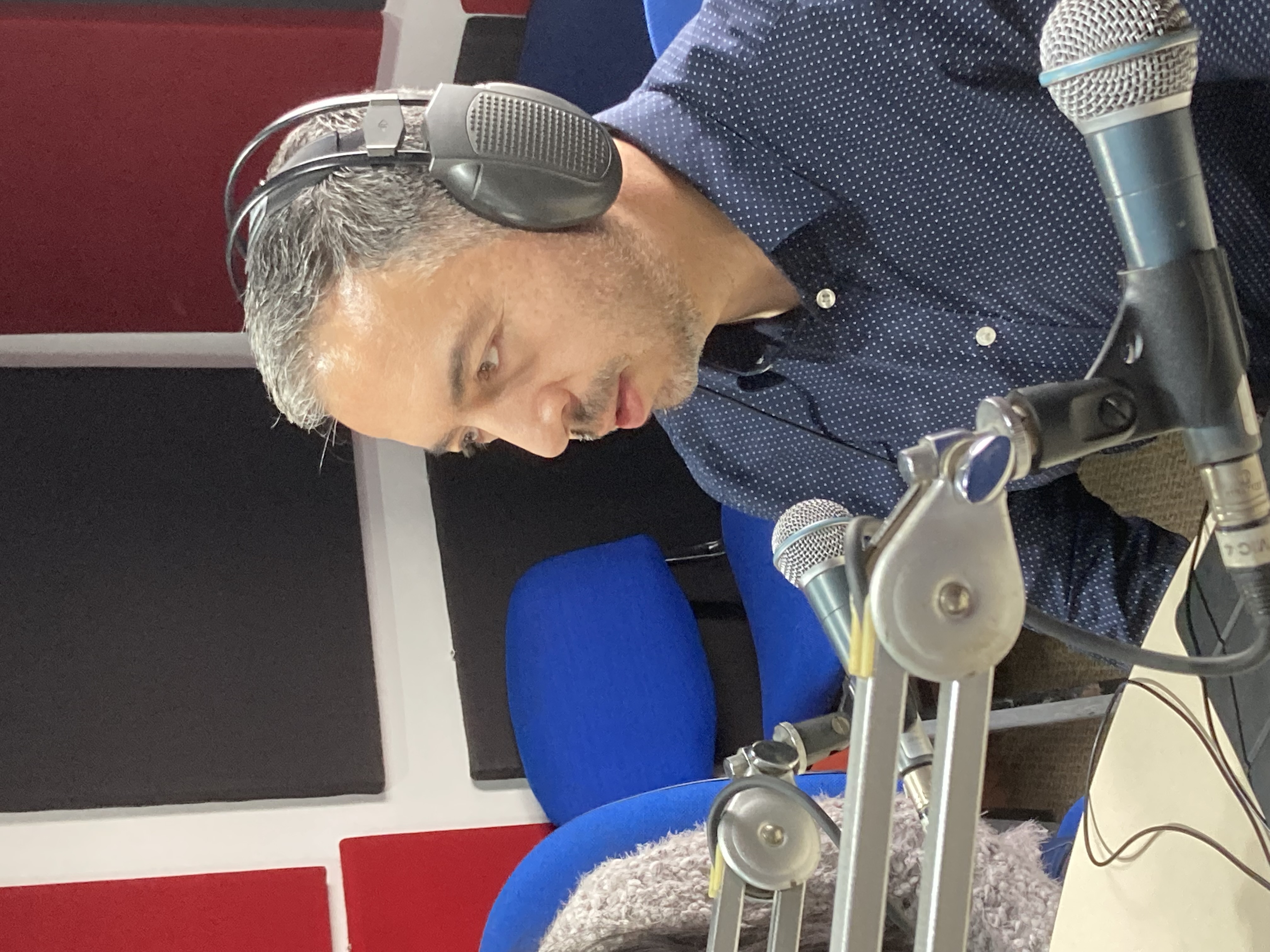 Profesor Alberto Barreto frente al micrófono, grabando un podcast sobre infografías accesibles.
